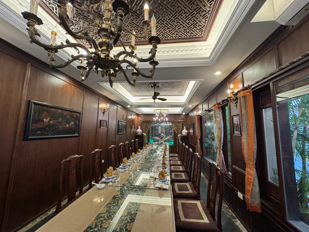 Phòng riêng VIP ốp gỗ với đèn chùm đồng và bàn tiệc dài